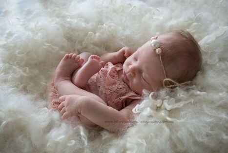 Beautiful newborn baby in white fur nest with pink outfit and headband